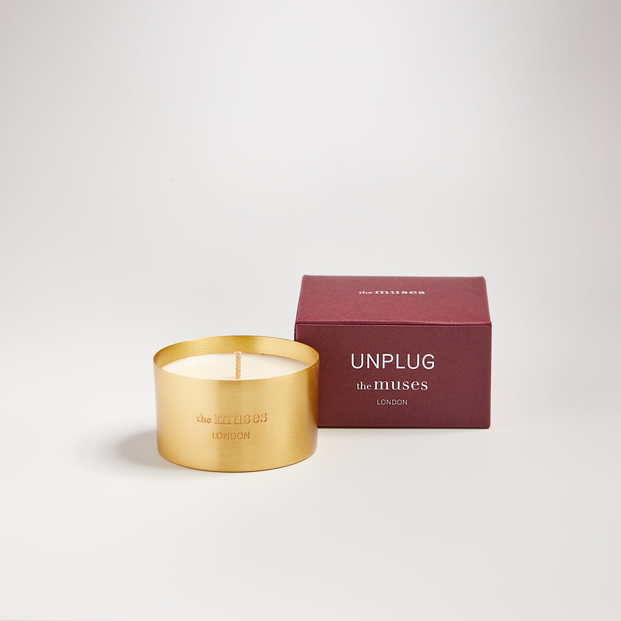 Unplug scented 100% natural wax candle 110g next to claret red candle box. Front